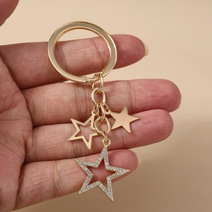 Vue détaillée des breloques étoiles dorées avec strass sur un porte-clés à la main