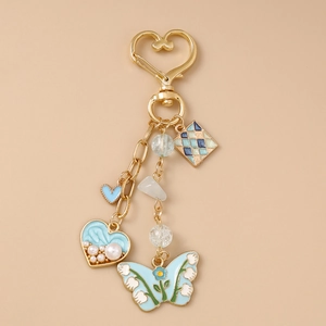 Detail of a golden heart hook keychain with blue enamel heart and butterfly charms