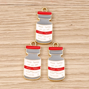 Détail de trois pendentifs émaillés en forme de flacon pour bijoux d'infirmière