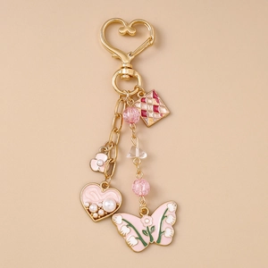 Detail of pink enamel heart and butterfly charms on a gold-plated fashion keychain