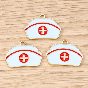 Gros plan de trois pendentifs de chapeau d'infirmière bleu clair avec croix rouge sur bois