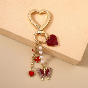 Detailansicht goldener Schlüsselanhänger mit Glitzerschmetterling, Herzanhänger und Perlen