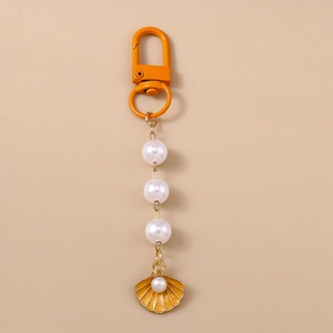 Detailed macro view of orange shell keychain with white pearls and enamel finish