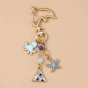 Porte-clés vie marine doré avec breloques poulpe et étoile de mer sur fond beige