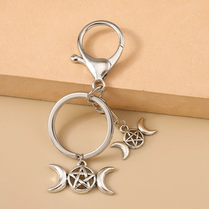 Gros plan d'un porte-clés en métal argenté antique avec pendentifs triple lune et pentagramme