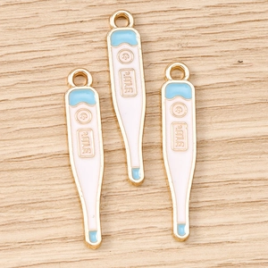 Vue macro de breloques thermomètre en alliage doré et émail pour la création de bijoux