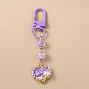 Macro detail of purple heart keychain with marble enamel and faux pearl accents