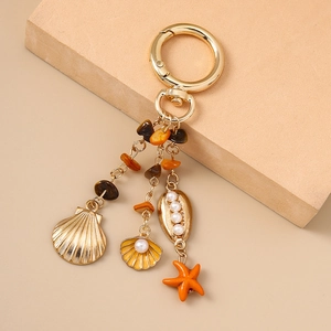 Détail d'un porte-clés doré avec étoile de mer, coquillage, perles et pierres colorées
