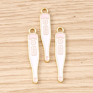 Vue macro de trois pendentifs thermomètres dorés en émail avec inscription 37.0°C