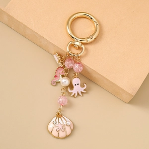 Détail des charms hippocampe, poulpe et coquillage en émail rose sur porte-clés doré