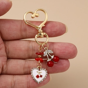 Porte-clés cœur cerise doré avec pendentif rouge et cœur en émail blanc serti de cristaux