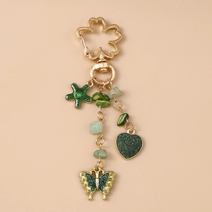 Details von grünem Schmetterling und Herzanhänger an goldener Kirschblüten-Kette