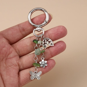 Détail de porte-clés argent vintage avec pierre verte naturelle, papillon et pendentifs