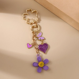 Detail eines lila Blumen-Schlüsselanhängers mit glitzerndem Herz und Schmetterling-Motiv