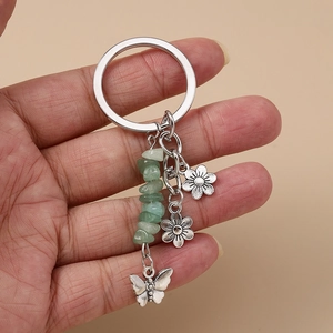 Détail du porte-clés en pierres vertes avec pendentifs papillon et fleur argent