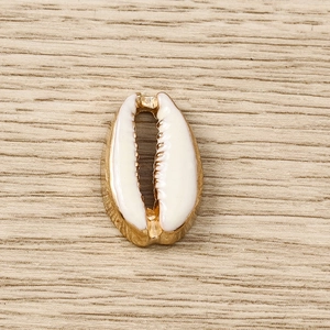 Macro shot of gold-plated shell pendant with white enamel on a light wood surface