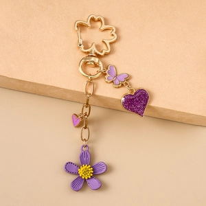 Detail von lila Blumen-Schlüsselanhänger mit Goldkette, Glitzerherz und Schmetterling