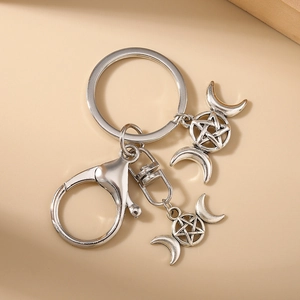 Détails des breloques lune triple et pentagramme sur un porte-clés en métal argenté