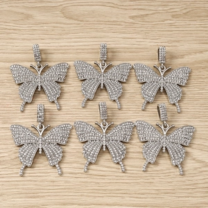 Set of 6 silver butterfly pendants with white rhinestones on a wood background