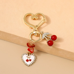 Détail d'un porte-clés cerise doré avec pendentif cœur et feuilles de strass