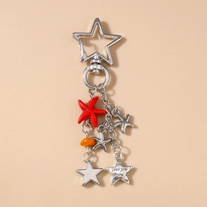Détail d'un porte-clés étoile de mer argenté avec étoile rouge et pendentif gravé love