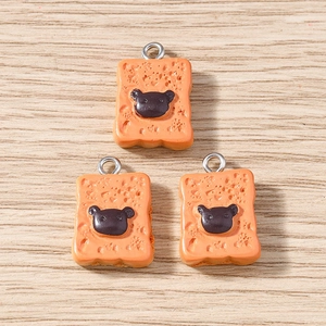 Detail showing three rectangular bread charms with bear motifs and silver loops