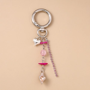 Détail du porte-clés argenté avec perles roses, breloque cœur et pendentif coquillage