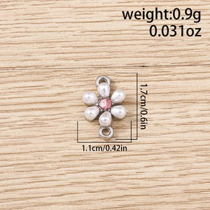 Detail view of flower jewelry charm with white pearls and pink crystal on wooden background