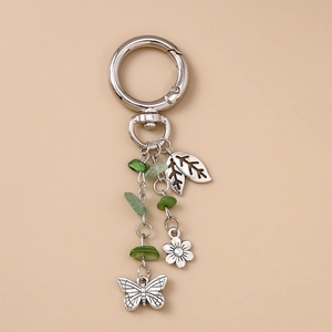 Vue détaillée du porte-clés en métal argenté avec perles vertes et pendentif papillon