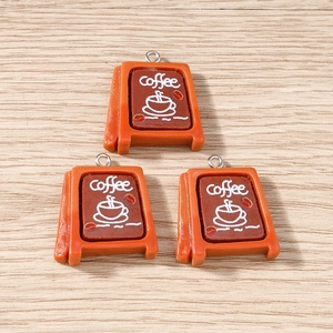 Dettaglio di ciondoli a forma di caffè con cuori e anelli di metallo su legno