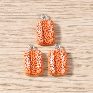 Detail of three baguette bread resin charms with silver rings on wood surface