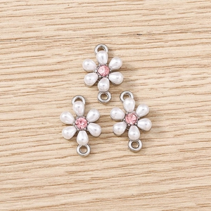 Detailed view of silver flower connector with white pearls and pink rhinestone center