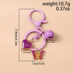 Detail of purple bell, glitter heart, and butterfly charms on a stylish metal keychain