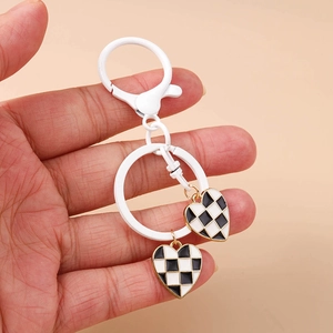 Detail of hand holding checkerboard heart pendants on white lacquered keychain