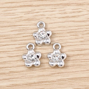 Macro shot of silver flower charms with clear rhinestones and top loops for DIY jewelry