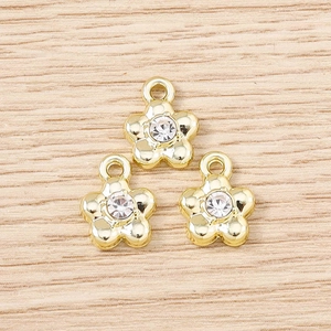 Macro view of three gold flower pendants with rhinestones on light wood background