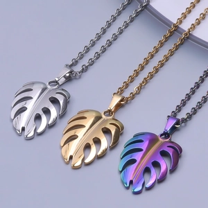 Detailed view of hollow monstera leaf pendants in gold, silver, and rainbow steel