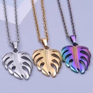 Detailed macro view of three monstera leaf pendants in gold, silver, and iridescent steel