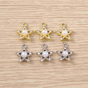 Detailed view of star-shaped jewelry charms with rhinestones and faux pearls on wood