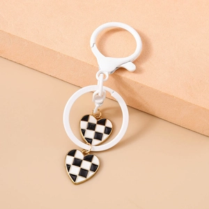 Detail of white metal keychain with double heart pendants in black and white checkerboard
