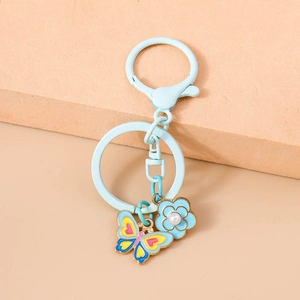 Detailed macro view of a light blue flower keychain with pearl and colorful butterfly charm