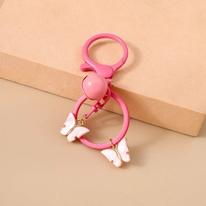 Close-up of pink butterfly keychain with matte finish bell and pearlescent charms