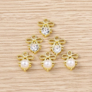 Detailed view of DIY bow and angel charms with pearls and rhinestones for jewelry making