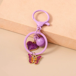 Detail of purple glitter heart and colorful enamel butterfly on metal keychain ring