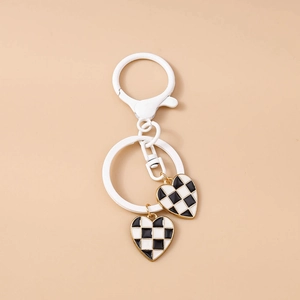 Close-up of heart pendants with black and white checkerboard patterns on a gold border keychain