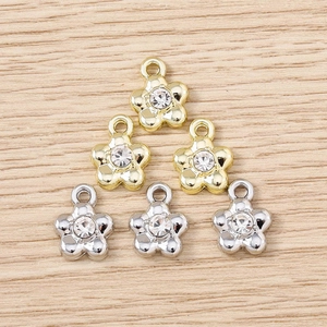 Detail of six flower metal pendants with white rhinestones on wood texture for DIY jewelry