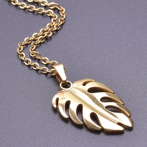 Macro shot of 18k gold plated monstera leaf pendant with a polished mirror finish