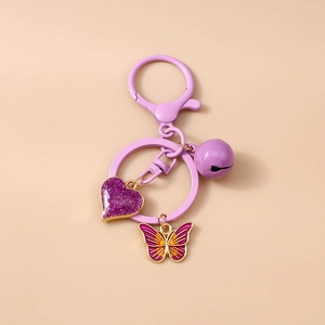 Detail of purple glitter heart, enamel butterfly, and bell on a stylish keychain