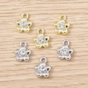 DIY flower charm pendants with rhinestones in gold and silver finish on wooden background