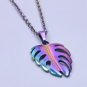 Macro detail of rainbow plated stainless steel monstera leaf charm with cut-out design